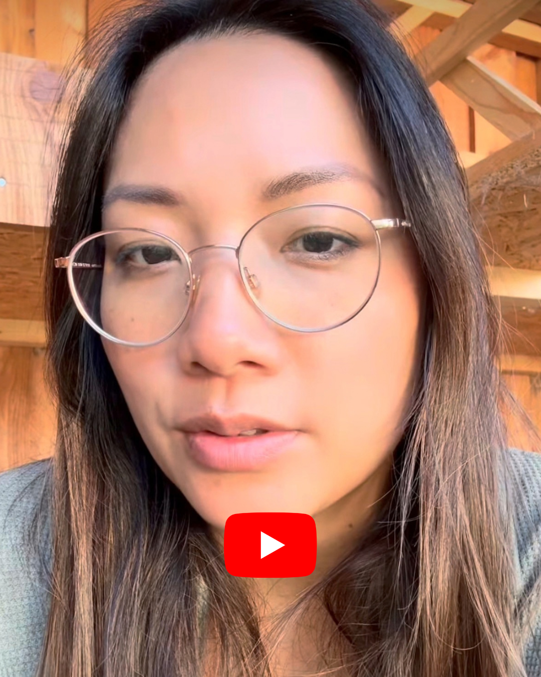 Nahaufnahme einer Person mit Brille vor einem hölzernen Hintergrund, die in einem Video über ganzheitliche Gesundheit spricht.